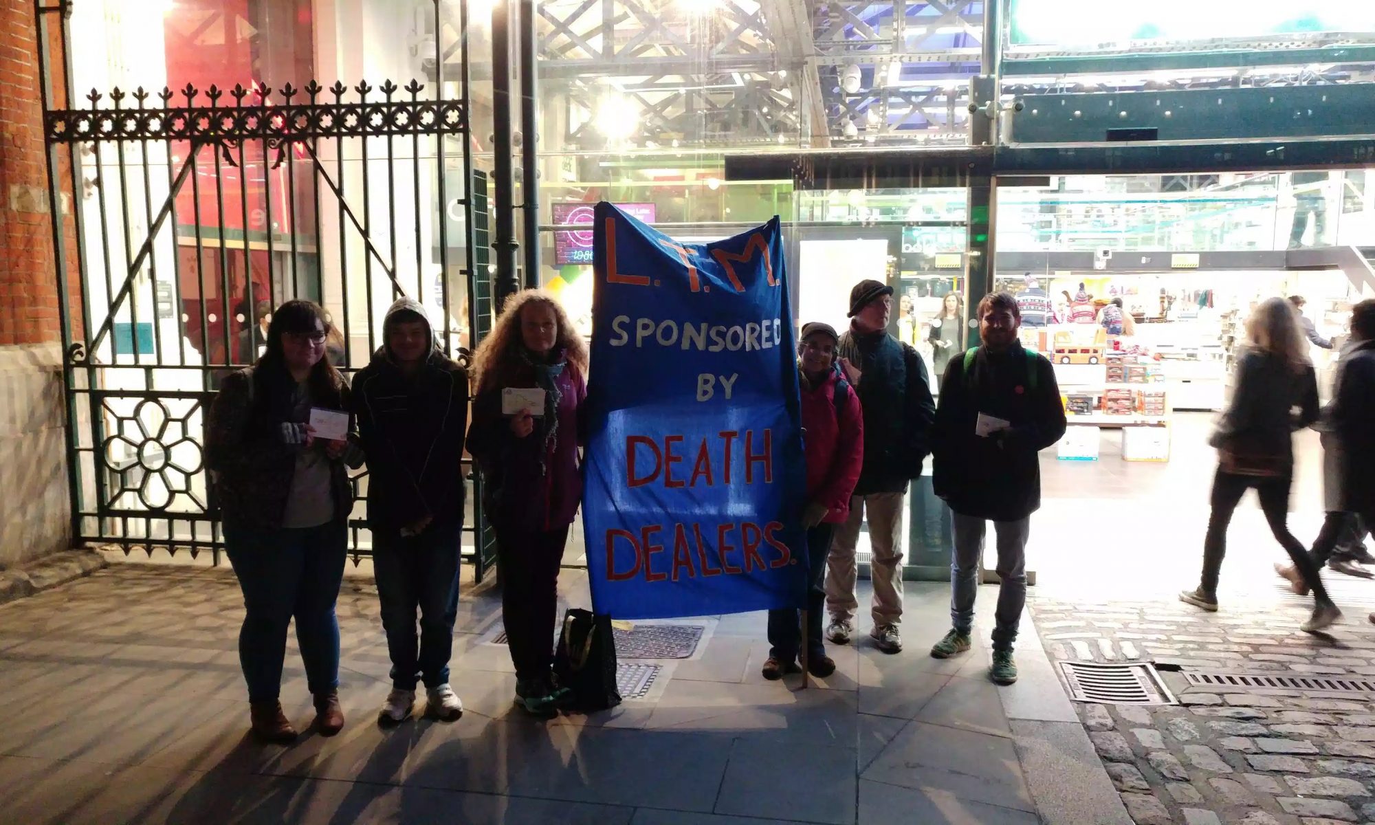 Activists hold banner 'LTM Sponsered by Death Dealers' outside transport museum